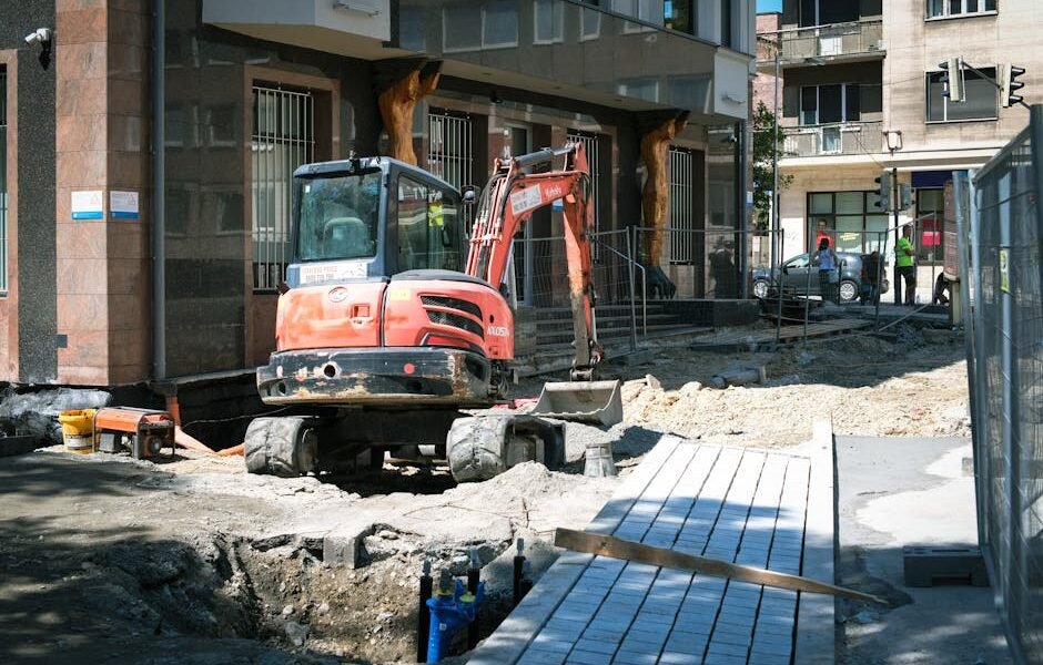 Ekskavatorius kasa tranšėją sklype – drenažo įrengimas namų valdoje ir grunto formavimo darbai