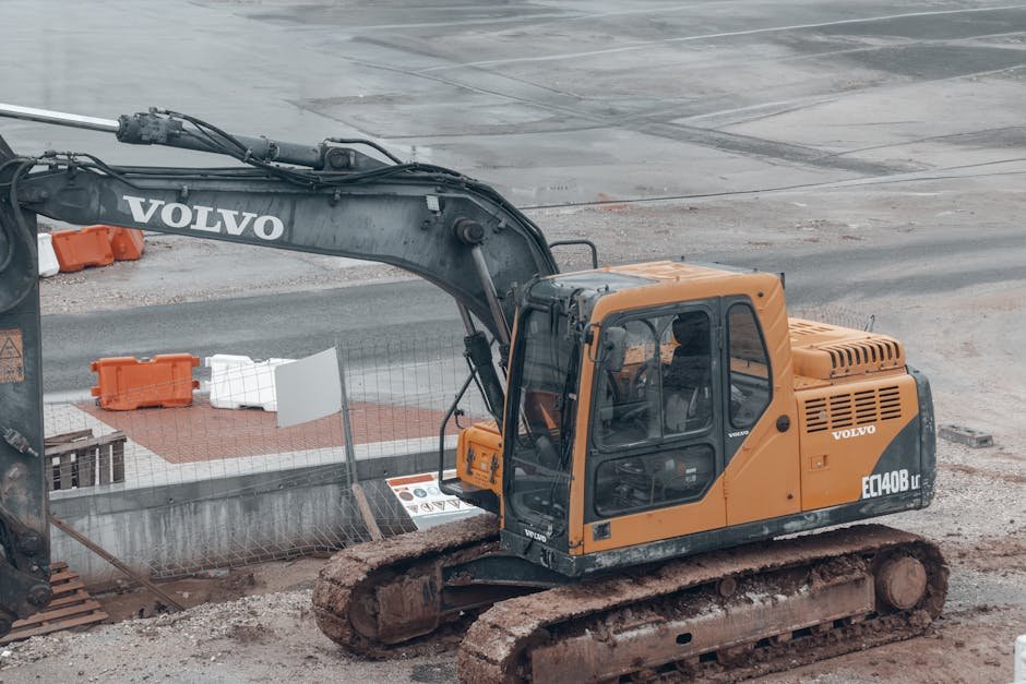 Worker cleaning an excavator radiator and engine area to remove dirt and debris