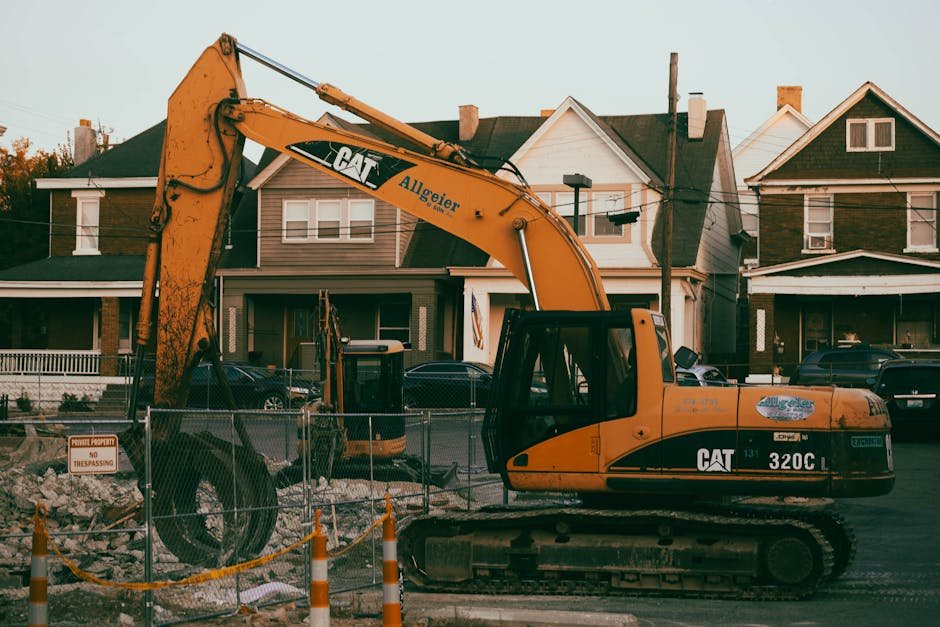 Excavator working carefully beside a house and fence in a tight residential yard