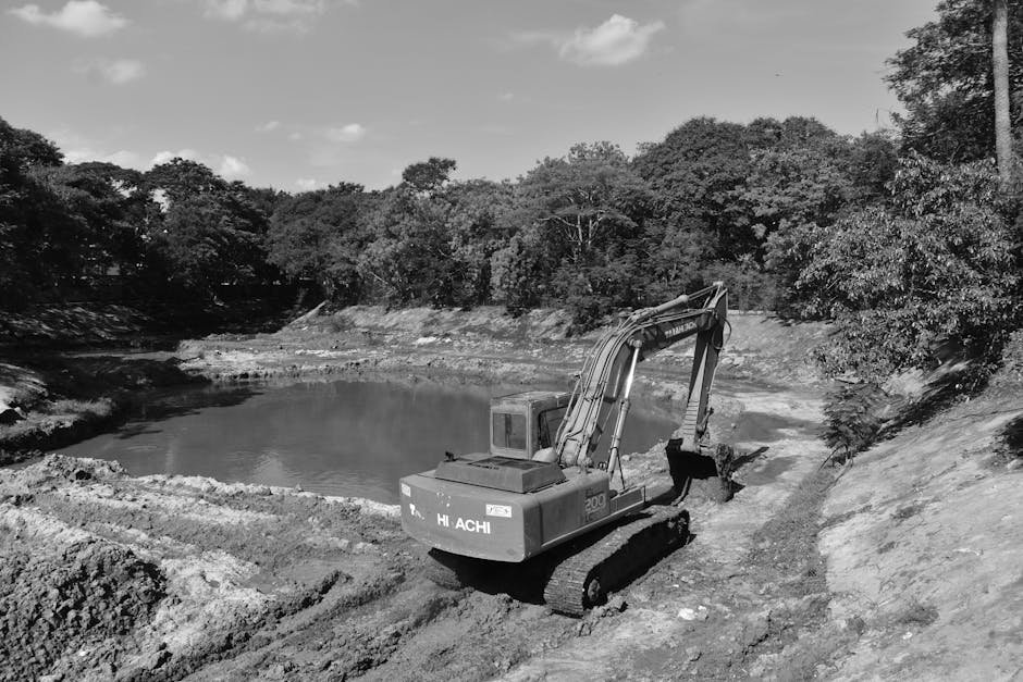 Excavator digging a pond in a rural area with exposed soil layers