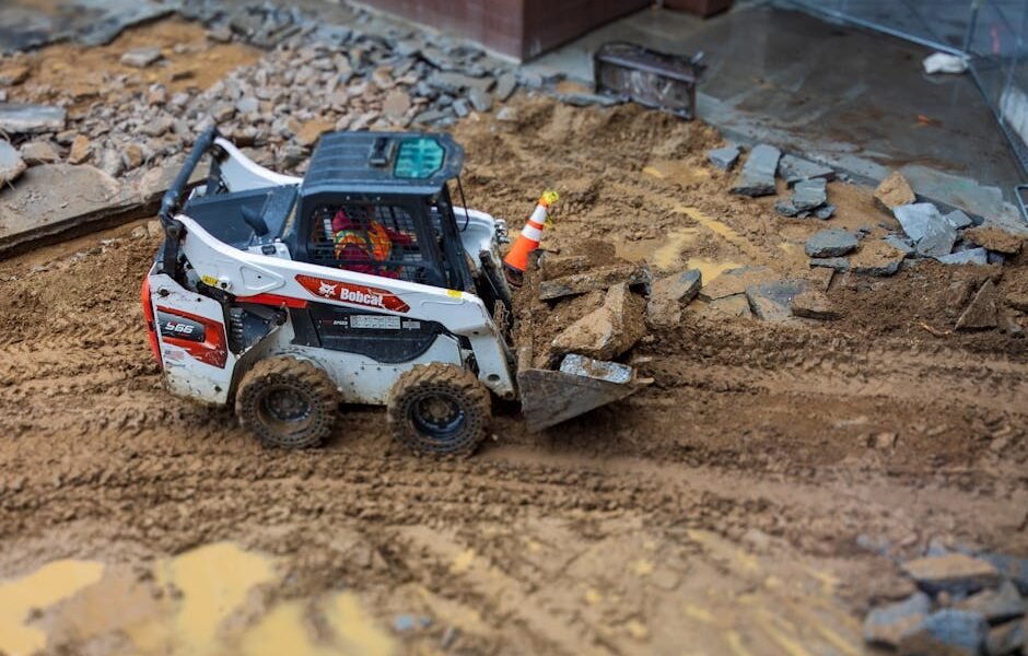 Bobcat ar mini ekskavatorius namuose ir sodyboje – mini ekskavatorius kasa žemę kieme.