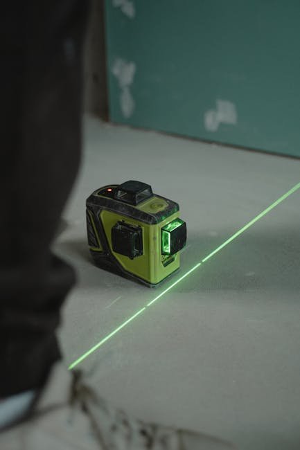 Worker measuring yard slope with a laser level and grade markers