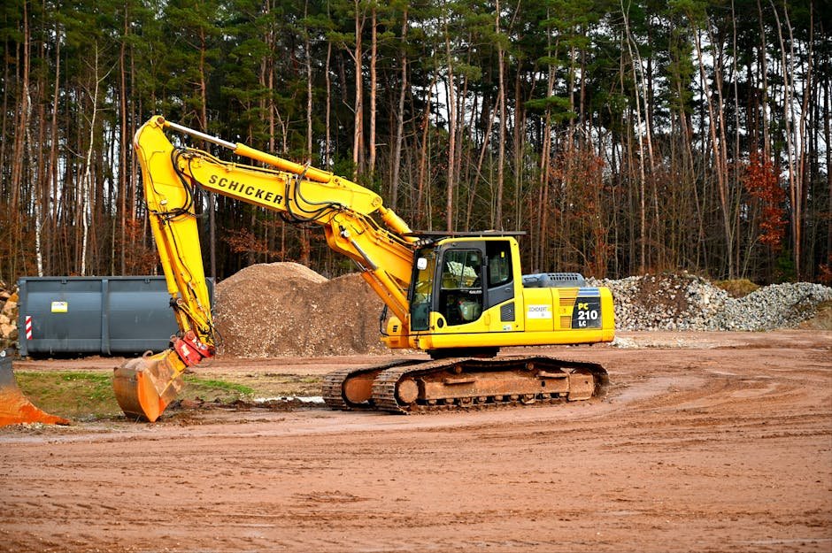 Excavator clearing an overgrown plot with roots and brush near a rural property