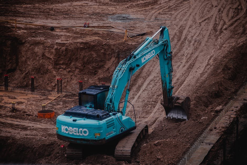Excavator working on a residential construction site with soil piles nearby