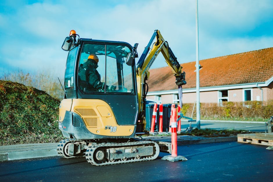 Mini excavator working in a narrow residential yard near a fence and house