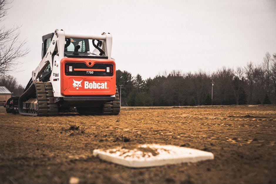 Bobcat leveling uneven soil in a residential plot to shape the terrain