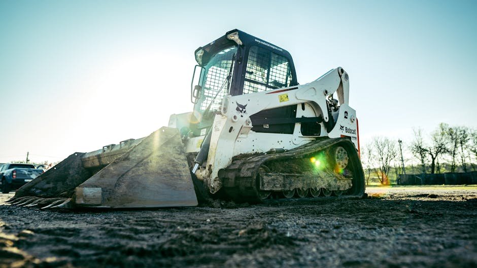 Skid steer loader driving on muddy ground at a construction site