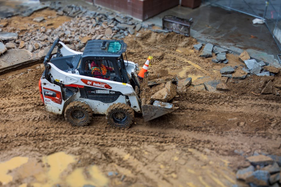 Skid-steer leveling soil on a yard before preparing the base for grass