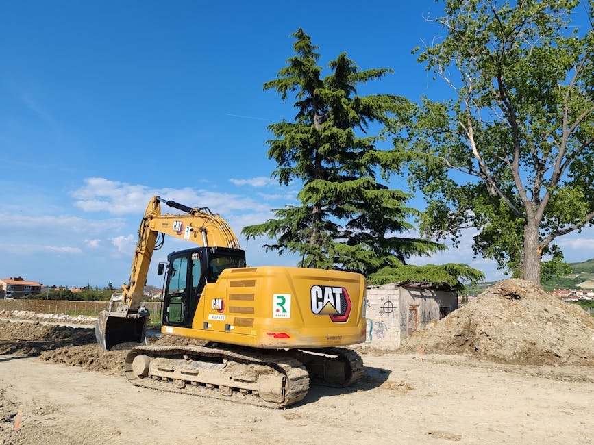 Excavator pulling a tree stump from the ground in a yard