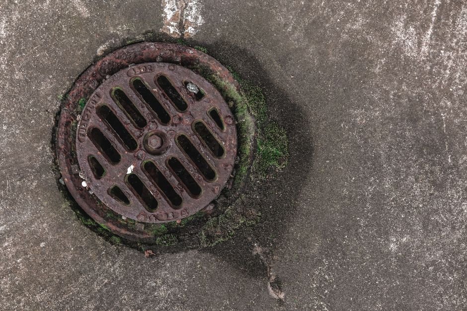 Person checking a yard drainage inspection chamber after heavy rain
